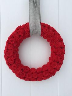 a red rosette wreath hanging on the side of a white door with a gray ribbon