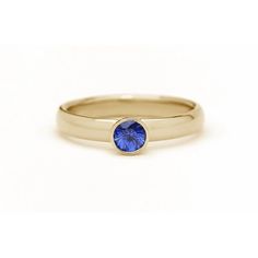 a yellow gold ring with a blue sapphire stone in the center, on a white background