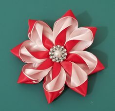 a red and white flower with a pearl center sitting on top of a green surface