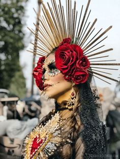 a woman with red roses in her hair and makeup is wearing an elaborate headdress