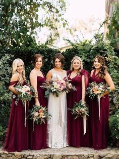 a group of women standing next to each other in front of some bushes and trees