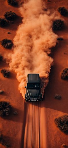 a truck driving through the desert with dust coming out of it