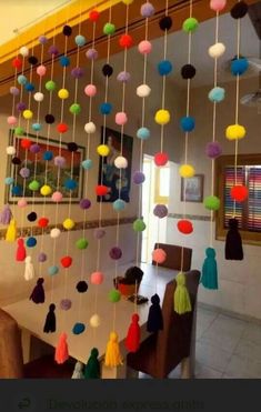 a dining room table with colorful balls hanging from the ceiling