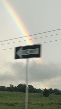 a street sign with a rainbow in the background