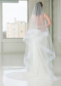 the back of a bride's dress is shown in front of a large window