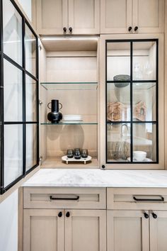 a kitchen with glass cabinets and marble counter tops