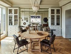 a large wooden table surrounded by chairs in a room with white walls and wood flooring