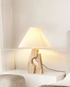 a lamp sitting on top of a white table next to a chair and footstool