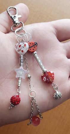 a hand holding a key chain with charms on it