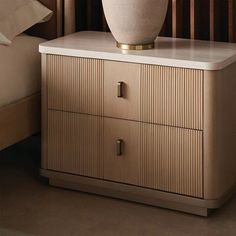 a large white vase sitting on top of a wooden cabinet next to a night stand