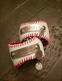 two baseballs with red and white stitching on them sitting on a wooden surface