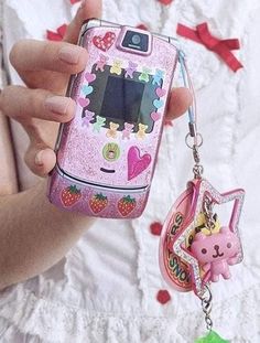 a person holding a cell phone with a keychain attached to it's side