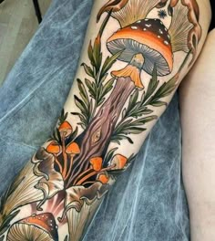 a woman's leg with tattoos on it and mushrooms growing out of the ground