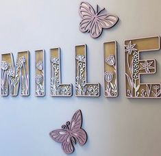 the word smile written in cut out letters with butterflies flying around it on a wall