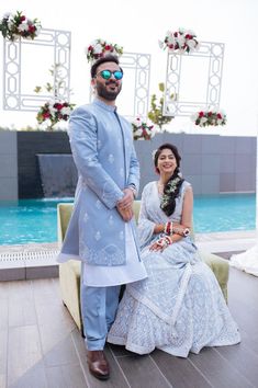 a man and woman sitting next to each other in front of a pool