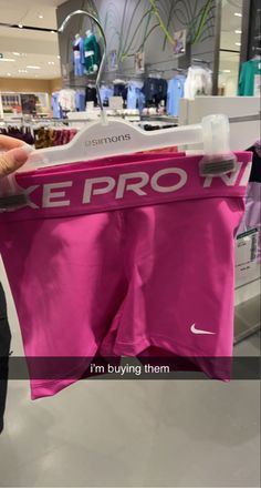 a person holding up a pink nike shorts in front of a store display with the words, i'm buying them