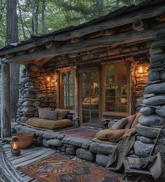 a log cabin with stone walls and flooring is lit by lanterns on the porch