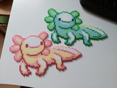 two cross stitch stickers sitting on top of a white table next to a computer keyboard