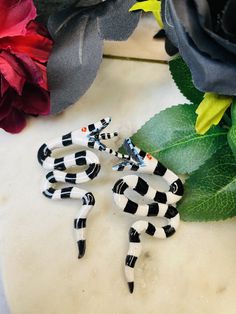 three black and white ceramic figurines sitting on top of a table next to flowers