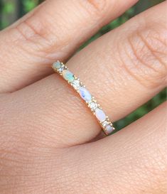 a woman's hand with a white opal and diamond ring on top of her finger