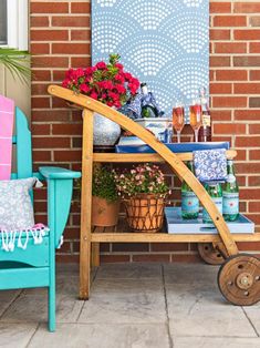 a wooden cart filled with bottles and flowers next to a brick wall in front of a blue chair