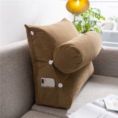 a couch with a pillow on it and an electronic device attached to the armrest