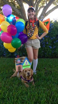 a woman standing in the grass with a dog and balloons