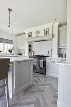 a kitchen with white cabinets and grey herringbone flooring is pictured in this image