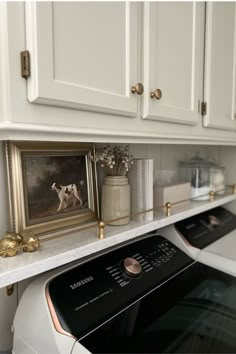 a white stove top oven sitting inside of a kitchen next to a painting on the wall