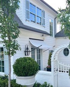 a white house with a large potted planter in front of it and an awning over the door