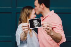 a man and woman holding up an old photo to show the baby's birth