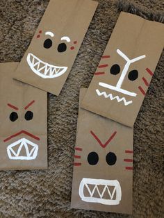 three brown paper bags with faces painted on them sitting on the floor next to each other