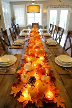 a long table is decorated with fall leaves and candles for the centerpieces,