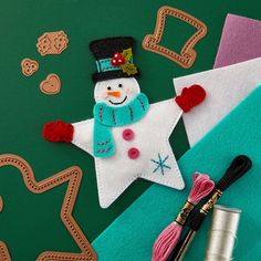 a snowman ornament is on top of some crafting supplies