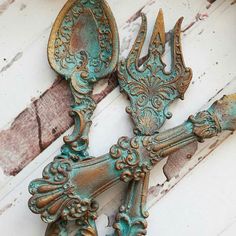 two old metal spoons sitting next to each other on a wooden surface with peeling paint