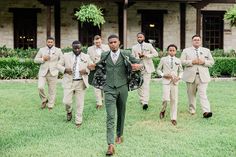 a group of men in suits walking across a lush green field