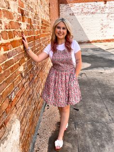 a woman standing next to a brick wall