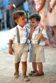 two young boys standing next to each other wearing suspenders and bow ties with their hands together