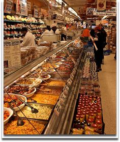 people shopping in a grocery store filled with lots of food