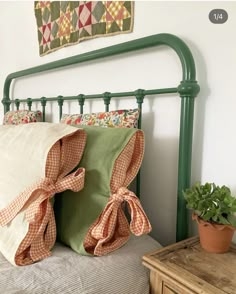 a green headboard with two pillows and a potted plant