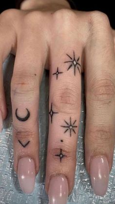 a woman's hand with three stars and moon tattoos on her left ring finger