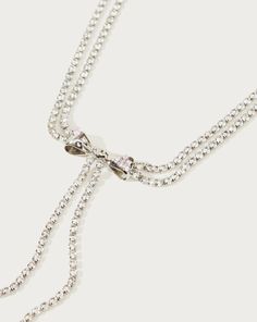 Materials: 18k platinum plated brass, cz stone Measurements: 410mm/16.1" in length, 70mm/2.8" in extension length. a captivating fusion of celestial charm and doll-inspired whimsy. This exquisite silver necklace showcases a charming bow tie droplet, its delicate strings cascading down like stardust trails. This silver Y2K x BarbieCore droplet isn't just an accessory; it's a cosmic statement piece that invites you to weave your own story amidst the stars, where the rules of style are yours to red Adjustable Sparkling Rhinestone Necklace, Adjustable Necklace With Decorative Bow For Party, Adjustable Necklace With Decorative Bow, Bow Choker Jewelry For Parties, Sparkling Rhinestone Necklace For Gift, Silver Jewelry With Decorative Bow As Gift, Elegant Bow Choker Jewelry, Silver Jewelry With Decorative Bow For Wedding, Silver Wedding Jewelry With Decorative Bow