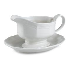 a white gravy dish and saucer set on a white plate with a spoon