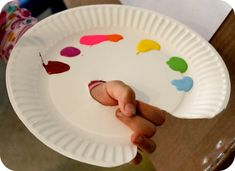 a person holding a paper plate with paint on it