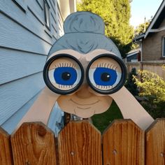 a paper doll with blue eyes peeking over a fence