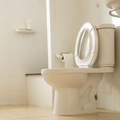 a white toilet sitting in a bathroom next to a wall mounted urinal and sink