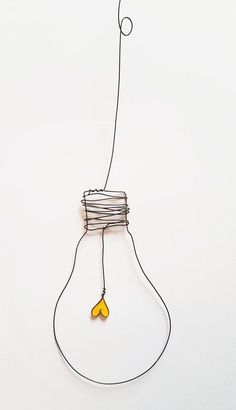 a wire sculpture with a lightbulb hanging from it's side and a string attached to the bulb