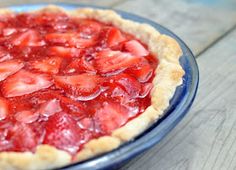 a close up of a pie with strawberries in it on a wooden table top