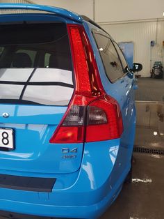 the back end of a blue car parked in a garage