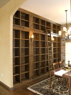 a dining room table and chairs in front of a bookshelf filled with shelves